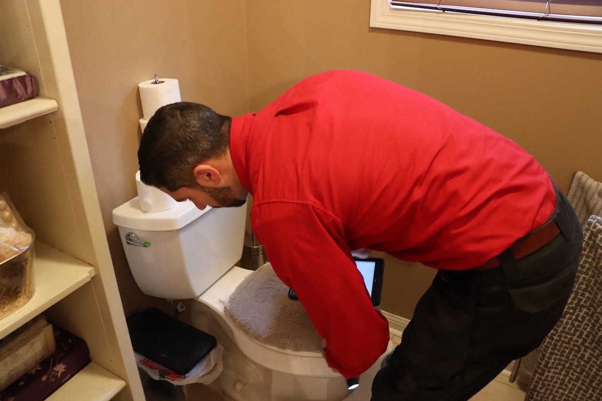 AtlasCare technician inspecting a toilet
